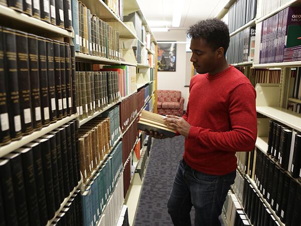 A student flips through a book in the stacks of Cooley Science Library.