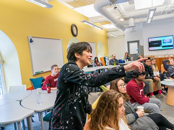 Professor Elodie Fourquet points to a screen while teaching a room full of students