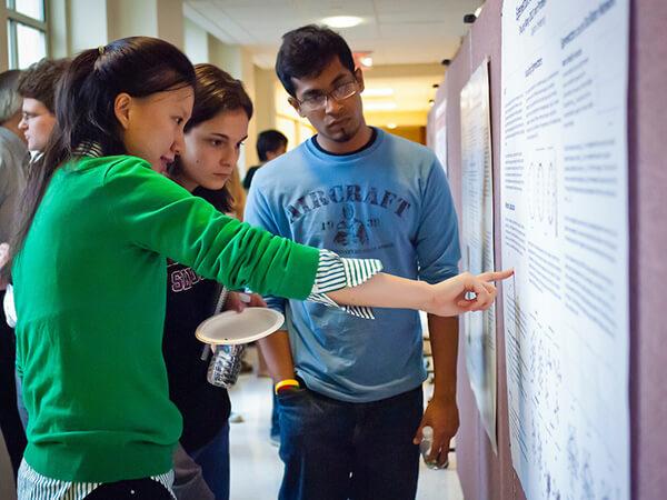 A mathematics student presents her research to professors and other students.