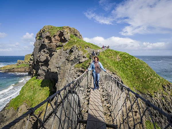 A student walks across a rope bridge in Ireland.