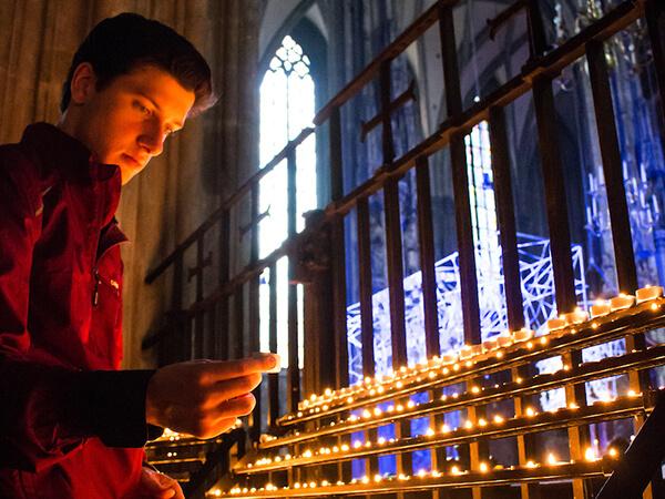 A Colgate student lights a votive candle in a centuries-old European cathedral.
