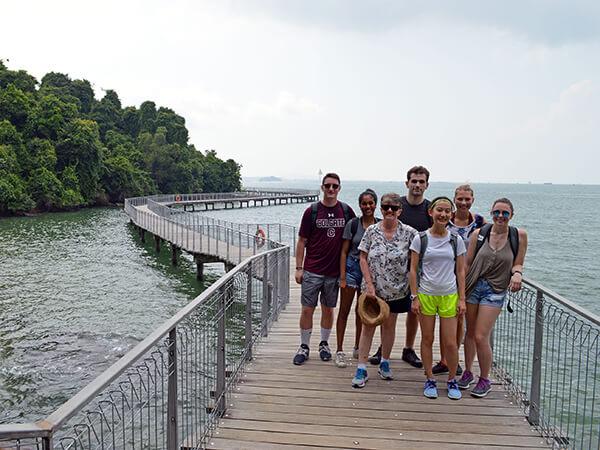 Professor Damhnait McHugh on a raised walkway with students in Singapore.