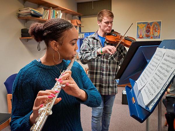 Colgate students playing a flute and a violin in a practice room
