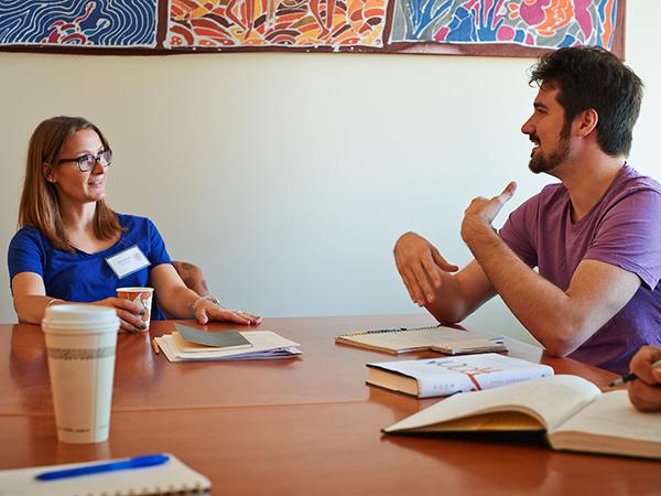 Student speaking with a presenter at an on-campus writers conference