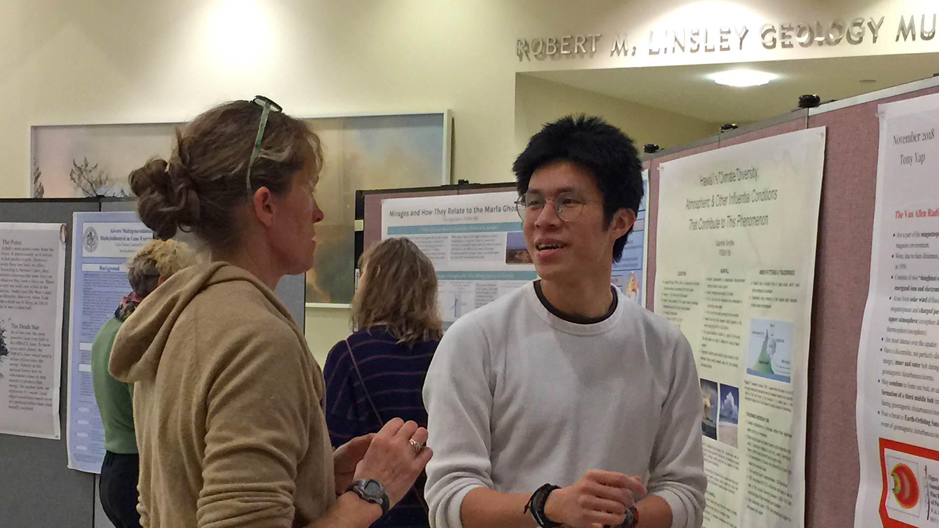 Professor Karen Harpp converses with a student about an academic poster at a symposium