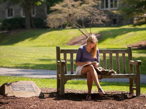 A student does homework on a bench.