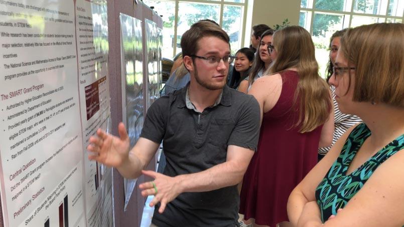 Jake Scott presents a poster to a faculty member