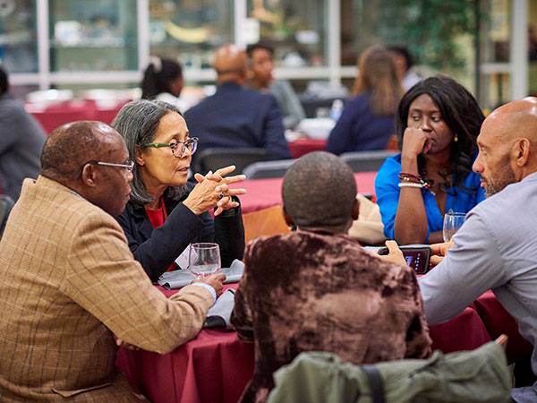 People gather around the table for discussion at Mosaic weekend.