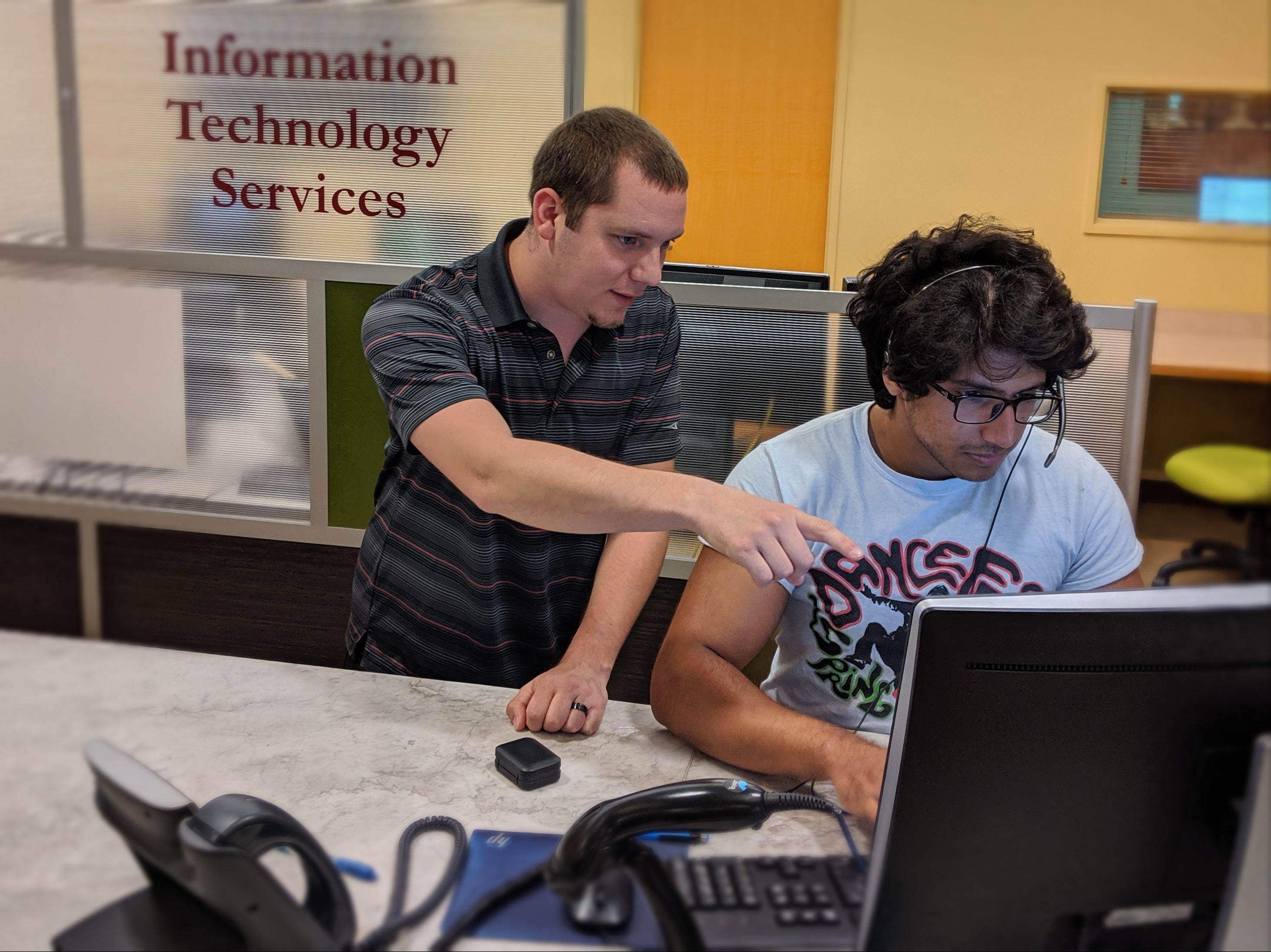 Two individuals looking at a computer screen.