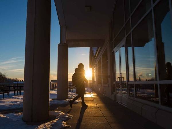 A student enters the at the top-floor entry to the library at sunset during winter