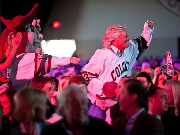 Richard branson charging through crowd wearing Colgate hockey jersey