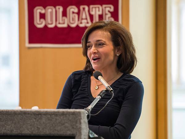Cheryl Sandberg at podium in front of Colgate banner