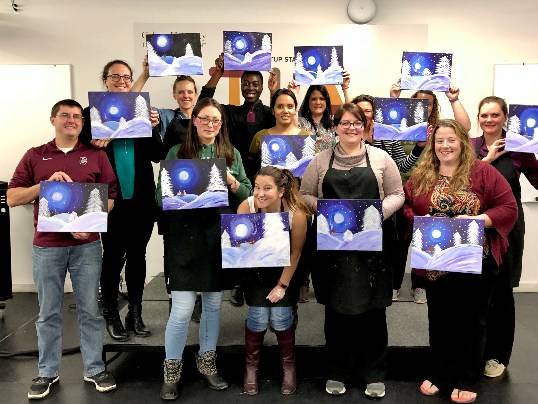 Colgate staff members show off the paintings they created at a Colgate Hello sponsored Wine and Sip