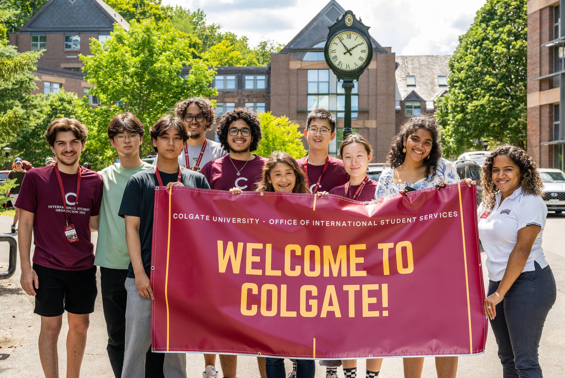 Group of international students and staff hold welcome sign on campus