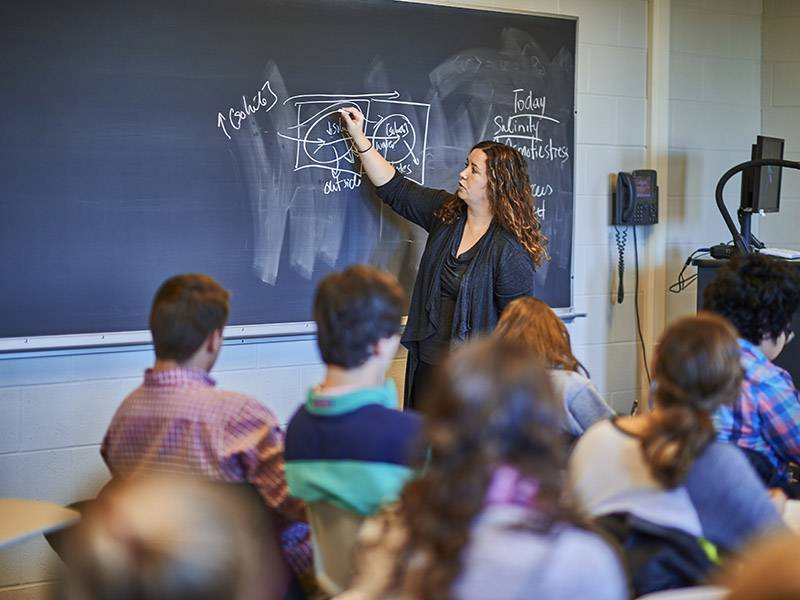 A professor writes on blackboard