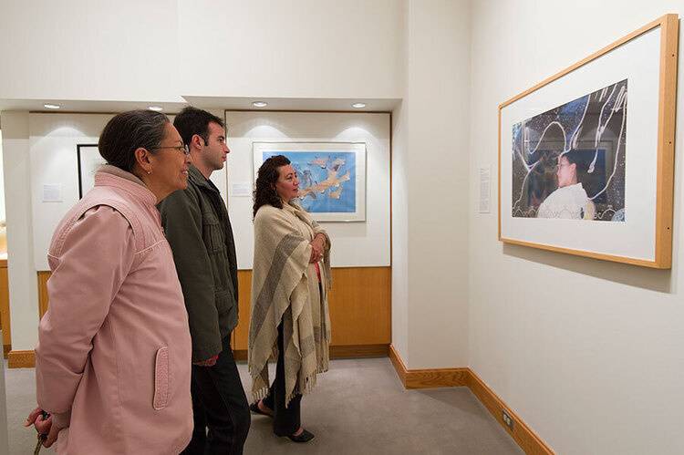 A group of three stand in front of artwork