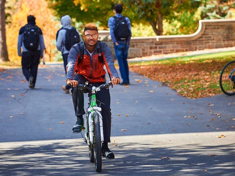 A student rides a bike on campus
