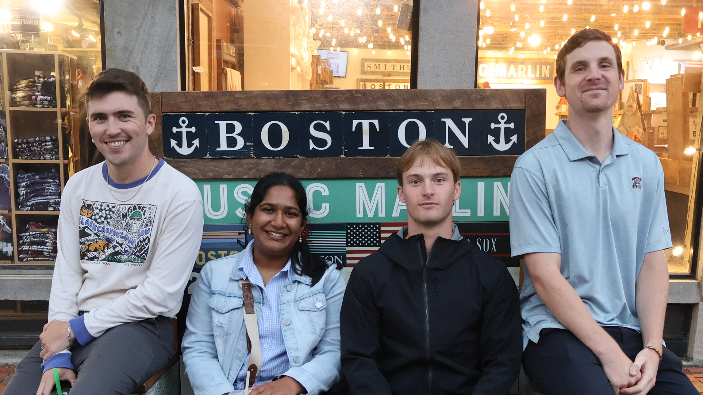 The four Summer 2024 Accelerator participants seated in front of a sign for Boston.
