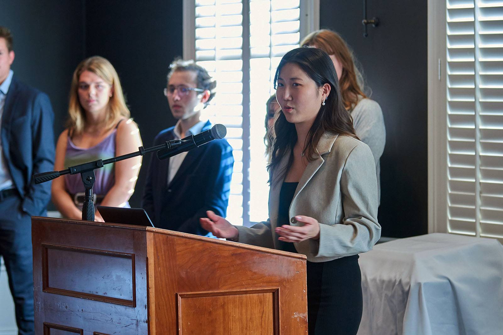 A student stands at a podium while speaking to an audience