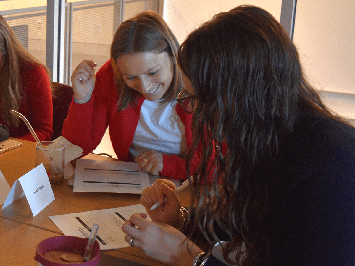 Two student leaders of Hami Down are seated at a table, smiling, looking over a document.