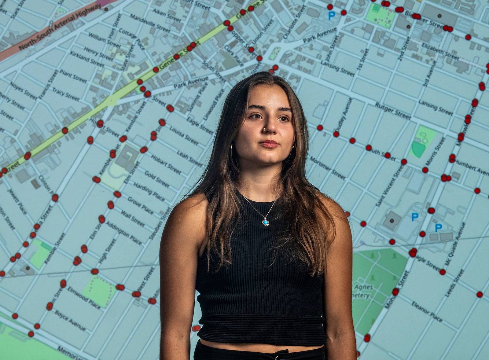 Sara Tabibian stands with a projected image of a GIS transportation map