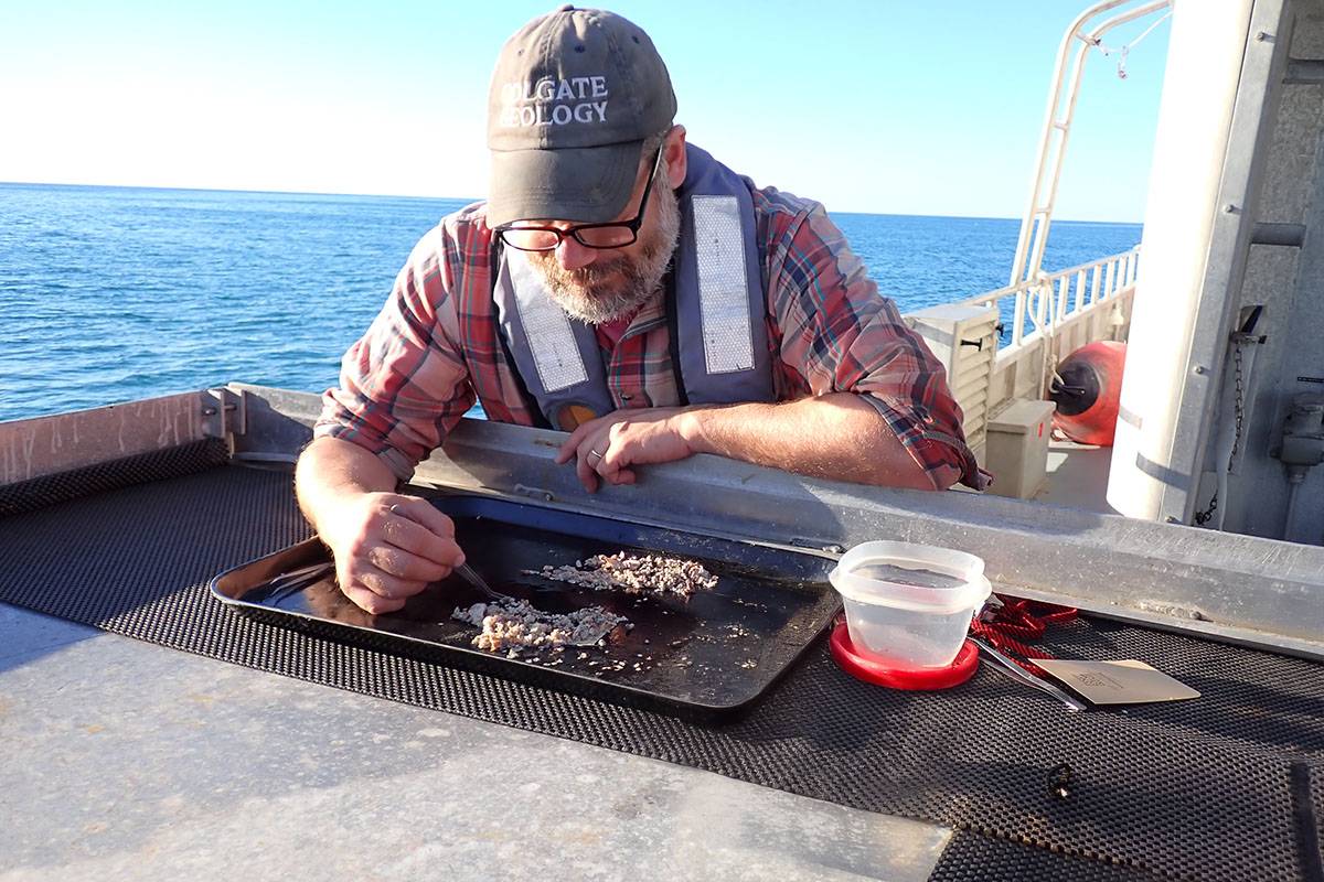 A faculty member sorting shells on a boat for research