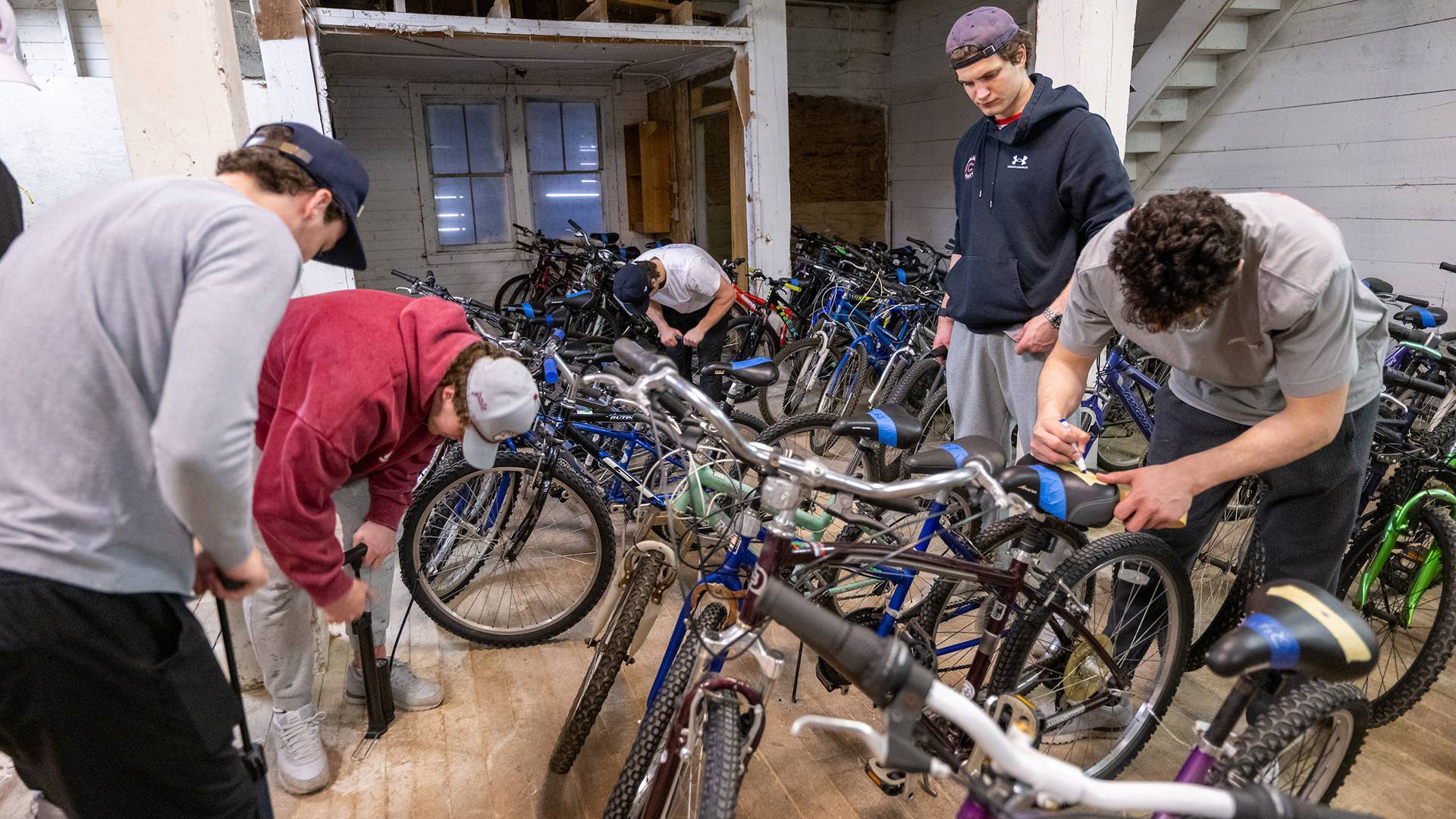 Students inside a warehouse sort bikes by size and add air to their tires.