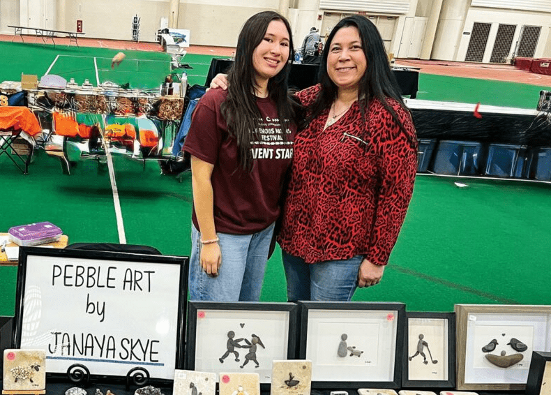 Janaya Jones '26 stands with her mother behind a display of her pebble art