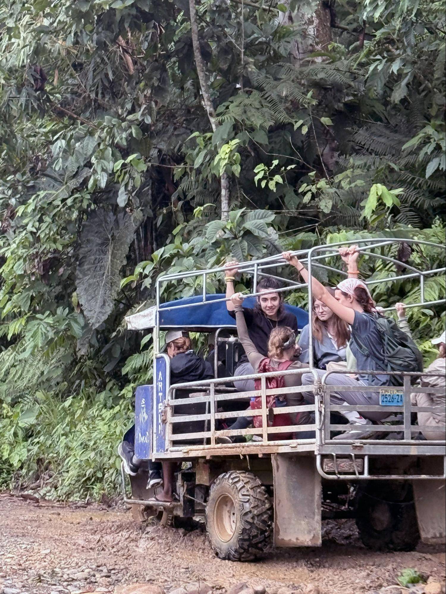 Students are transported in an all-terrain vehicle through the muddy landscape.