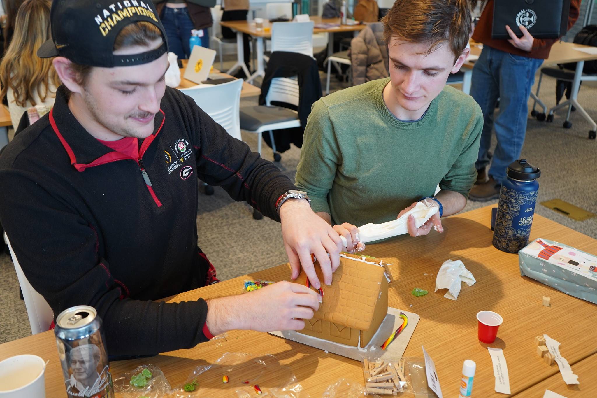 Two students construct a gingerbread house