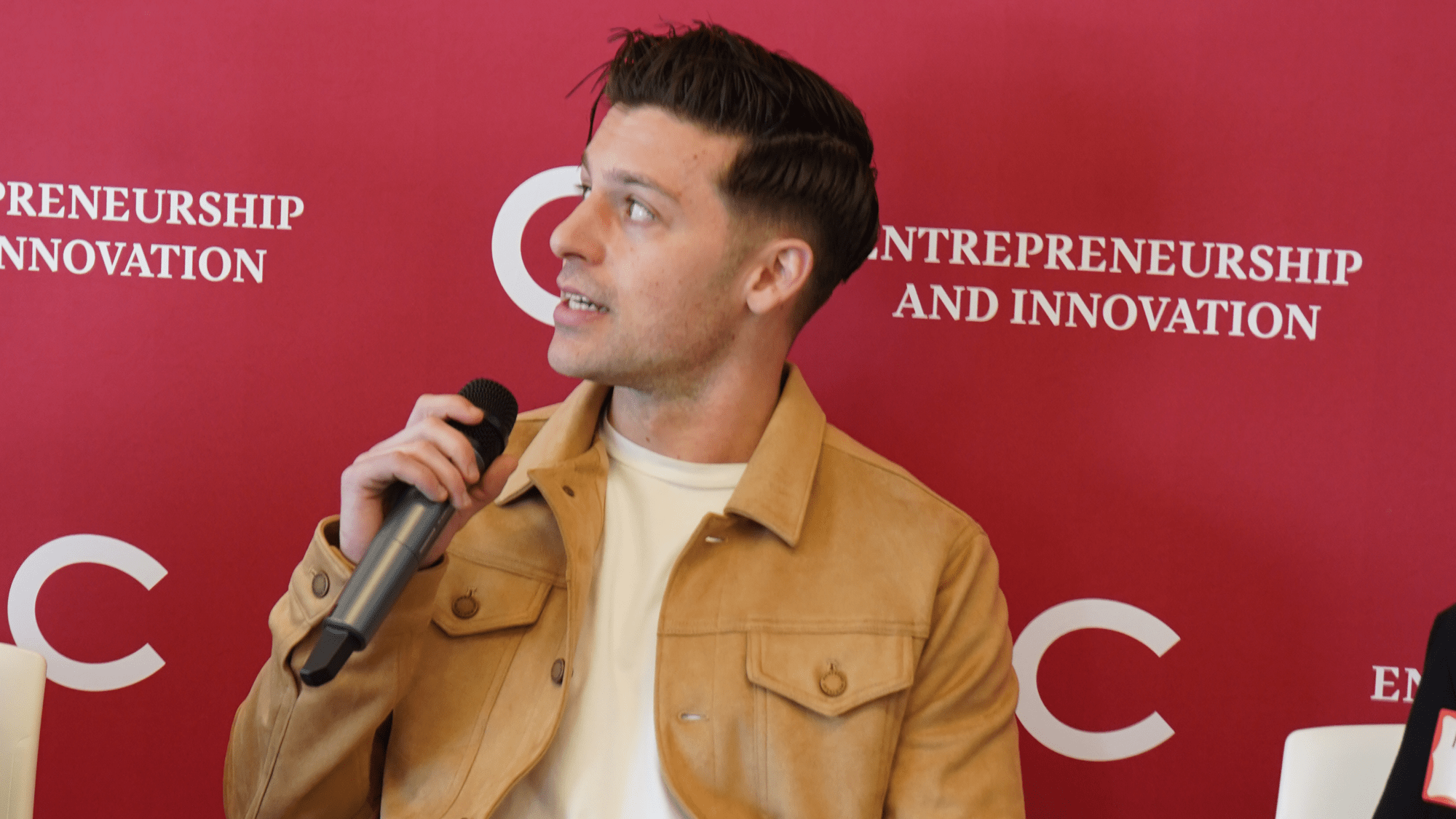 Nick Freud holding a microphone while speaking at a TIA Incubator session.