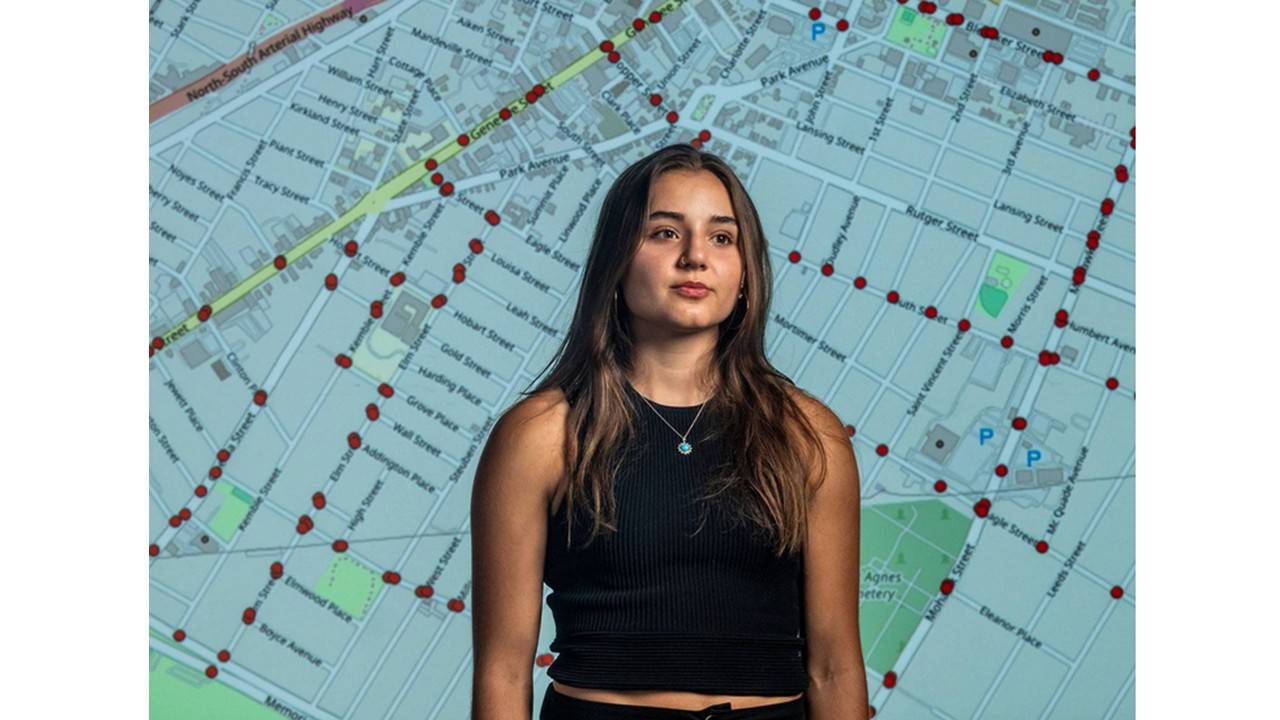 Sara Tabibian ’26 in front of a road map of Utica, N.Y.