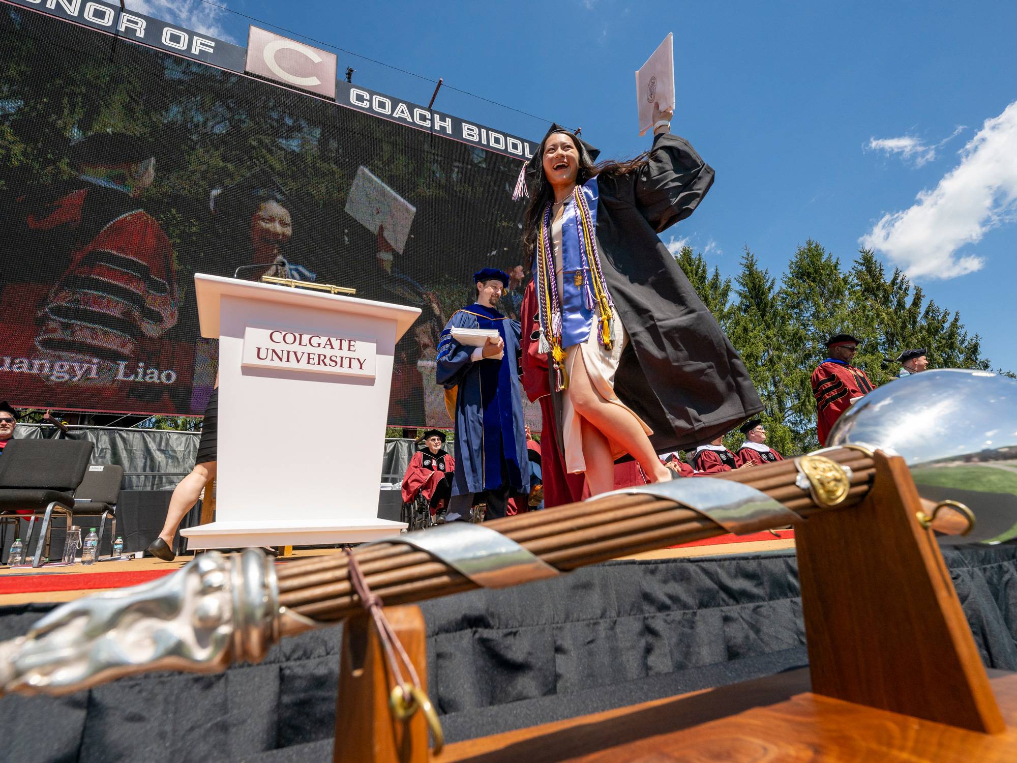 Student walks across commencement stage holding diploma.