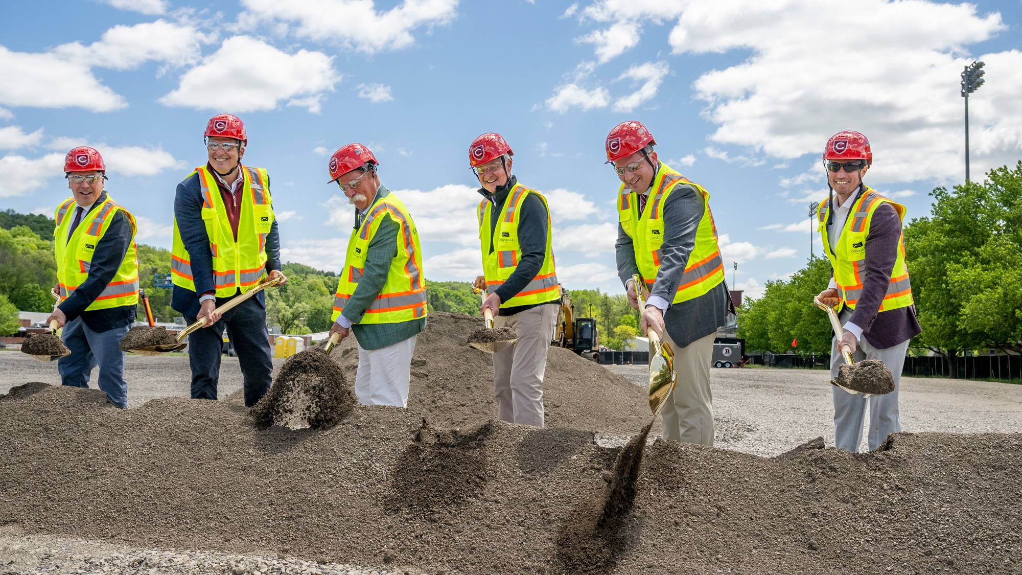Six people wearing hardhats and holding shovels