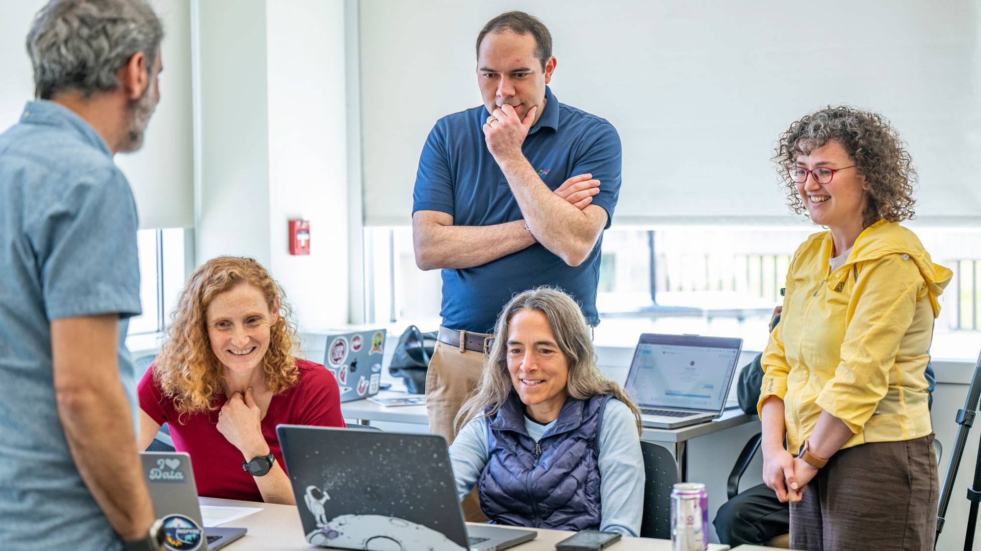 Professors and staff look at laptop